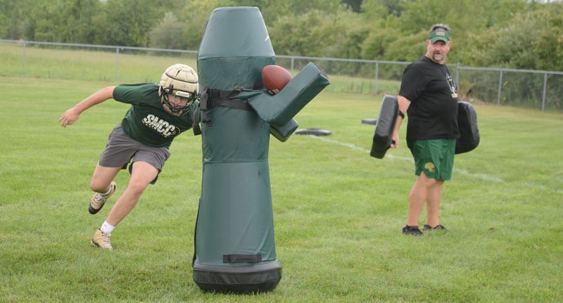 Harrison Tyner attacks a blocking dummy as assistant coach Nate Geiger looks on during the first football practice of the season for St. Mary Catholic Central's football team on Monday, Aug. 10, 2026.