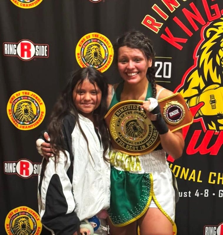 Holland boxer Emily Martinez celebrates with her daughter after winning the King of the Jungle tournament title on Saturday, Aug. 9 in Grand Rapids.