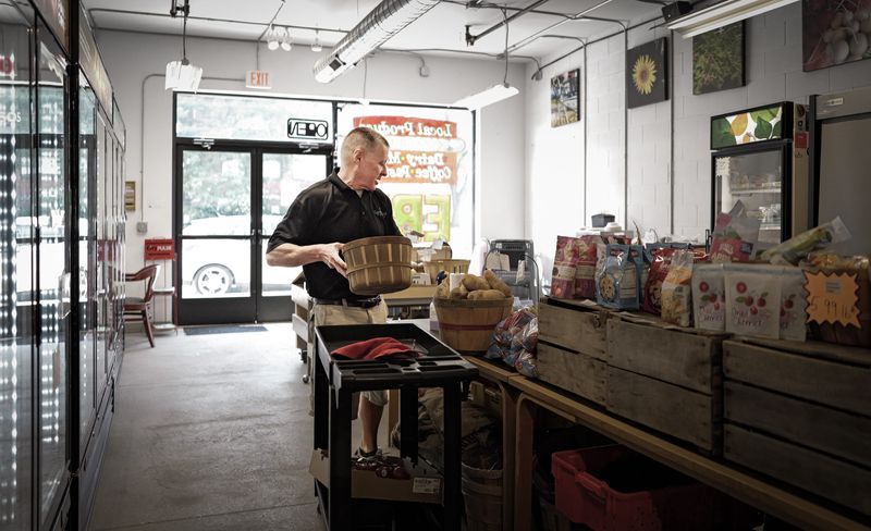 Eastside Lansing Food Co-Op Store Manager Gary Snow stocks fresh vegetables on Friday, Aug. 14, 2026.