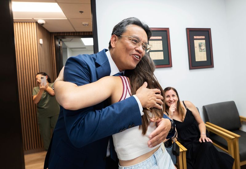 Plastic surgeon Dr. Kongkrit Chaiyasate, is hugged by Aliz Cservenak, 13, of Hungary, as she visits his office in West Bloomfield on Wednesday, August 5, 2026, to go over an update after a revision procedure performed by the doctor in collaboration with Trinity Health Oakland to reconstruct her nose after she developed a severe infection while battling cancer while in a Hungary hospital that disintegrated the bones in her nose and face. The infection caused her to lose er nose, part of her palate and upper jaw.