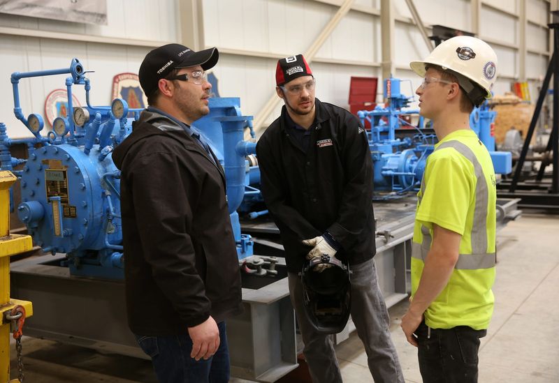 Millwright coordinator and instructor Carles (cq) Hicks, left, talks with students Charles Kelly,27, center, and Jake Atkins, 21, at the Wayland Carpenter and Millwright Training Center in Wayland, Michigan.