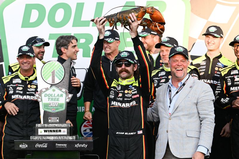 Team Penske driver Ryan Blaney, center, holds up one of his prizes, Loudon the Lobster, after winning the Dollar Tree 301 at New Hampshire Motor Speedway.