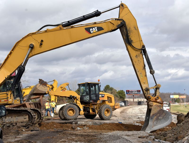 A front-end loader, center, dumps aggregate into a large steel box as an excavator distributes the aggregate backfill into a hole as workers install a 43-inch storm-sewer pipe along I-275 southbound, just north of the Tyler Rd. bridge, Thursday, April 7, 2022.