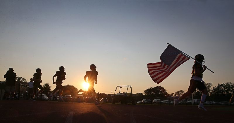 The McQuaid Knights race onto the field as the sun sets, to face UPrep in their Section V matchup Friday night, Sept. 9, 2022 at McQuaid Jesuit High School.