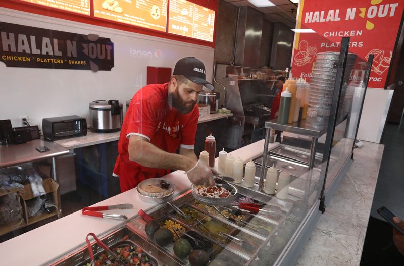 Naz Mayan piles toppings onto a NYC Halal Platter at his new Halal N Out restaurant.