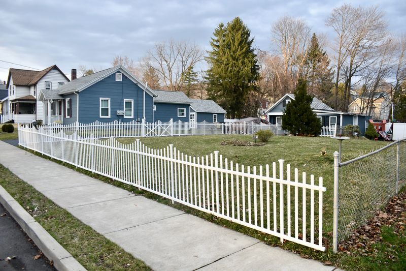 A  white picket fence surrounds the empty lot at 20 Milford St., the site of a 2011 fire that claimed the life of 17-year-old Jeffrey Aissa.