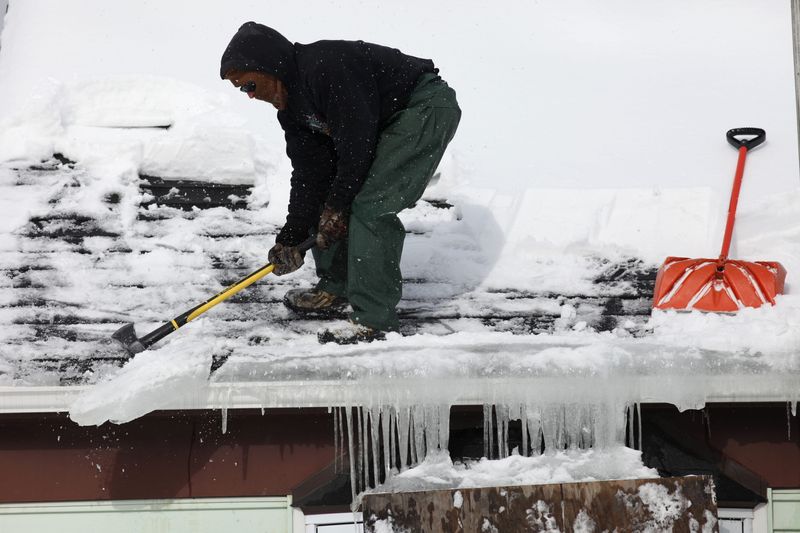 Doug Tanner removes an ice dam from a home in Irondequoit using the blunt end of an ax. Tanner works for Graves Bros. Home Improvement Co. This photograph was taken in February, during the middle of our deep freeze.