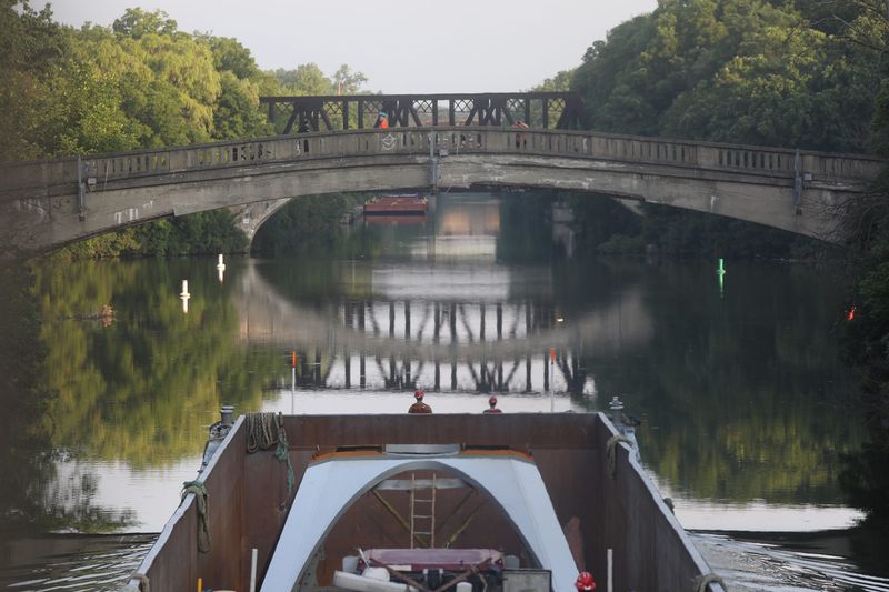 The Carver Companies barge heads through Genesee Valley Park around 7 a.m., some people came out to watch it.