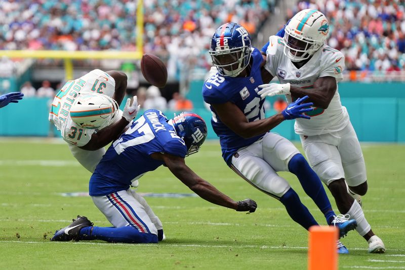 Oct 8, 2023; Miami Gardens, Florida, USA; New York Giants safety Jason Pinnock (27) knocks the ball loose from Miami Dolphins running back Raheem Mostert (31) during the first half at Hard Rock Stadium. Mandatory Credit: Jasen Vinlove-USA TODAY Sports