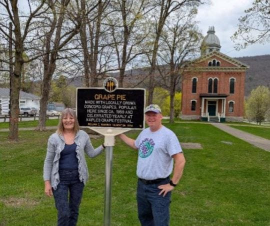 Naples Historical Society President Trish Lambiase and John French, president of the Naples Grape & Arts Festival, pose in front of the new grape pie historical marker in front of Naples Memorial Town Hall.