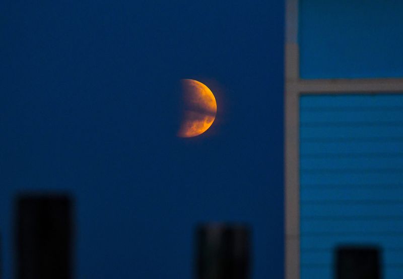 A a full flower moon being partially eclipsed can be seen May 26, 2021 at dawn over the Banana River in Cocoa Beach, Florida.