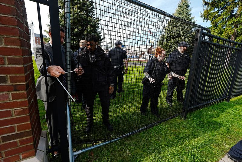 University of Rochester Public Safety officers zip tie a portable gate to the stationary ones at Fauver Stadium on May 16, 2025 as UR graduate students and supporters protested across the street before the university's commencement ceremony about the university not allowing a fair process vote for a union election.