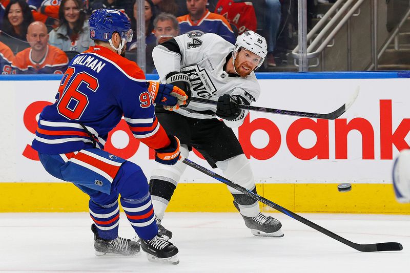 Apr 27, 2025; Edmonton, Alberta, CAN; Los Angeles Kings defensemen Vladislav Gavrikov (84) gets a shot away in front of Edmonton Oilers defensemen Jake Wahlman (96) during the second period in game four of the first round of the 2025 Stanley Cup Playoffs at Rogers Place.