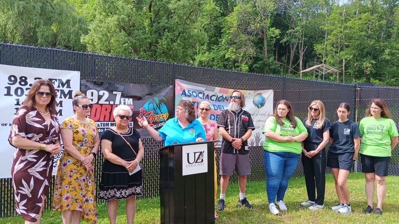 Mindy Barstein, owner and general manager of 92.7 FM The Drive and owner of El Zorro Radio Latino 98.3 FM, center, speaks at Utica Zoo on July 1, announcing Mesta Fiesta.