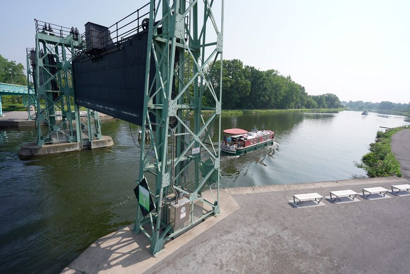 A packet boat heads east passing under guard gate 12 and the new pedestrian bridge in Brockport that crosses the Erie Canal and connects to the SUNY Brockport Campus on July 15, 2025.