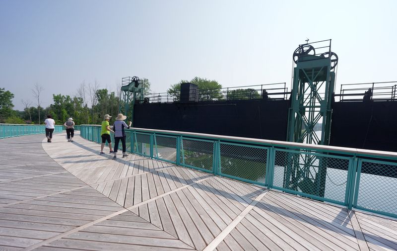 A few people walking along the Erie Canal stop on the new pedestrian bridge in Brockport that crosses the Erie Canal and connects to the SUNY Brockport Campus and takes in the view on July 15, 2025. The bridge opened in June.