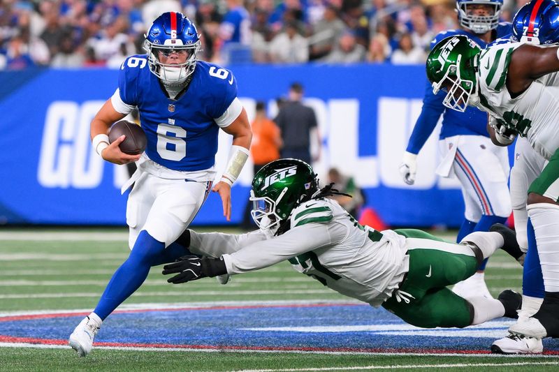 Aug 16, 2025; East Rutherford, New Jersey, USA; New York Giants quarterback Jaxson Dart (6) runs as New York Jets defensive end Kingsley Jonathan (57) defends during the first half at MetLife Stadium. Mandatory Credit: Rich Barnes-Imagn Images