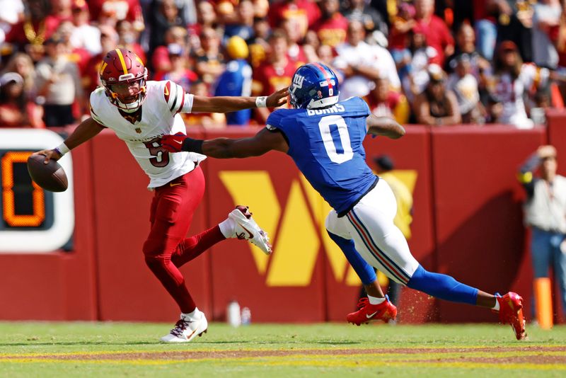 Sep 7, 2025; Landover, Maryland, USA; Washington Commanders quarterback Jayden Daniels (5) runs the ball during the fourth quarter against New York Giants linebacker Brian Burns (0) at Northwest Stadium. Mandatory Credit: Peter Casey-Imagn Images