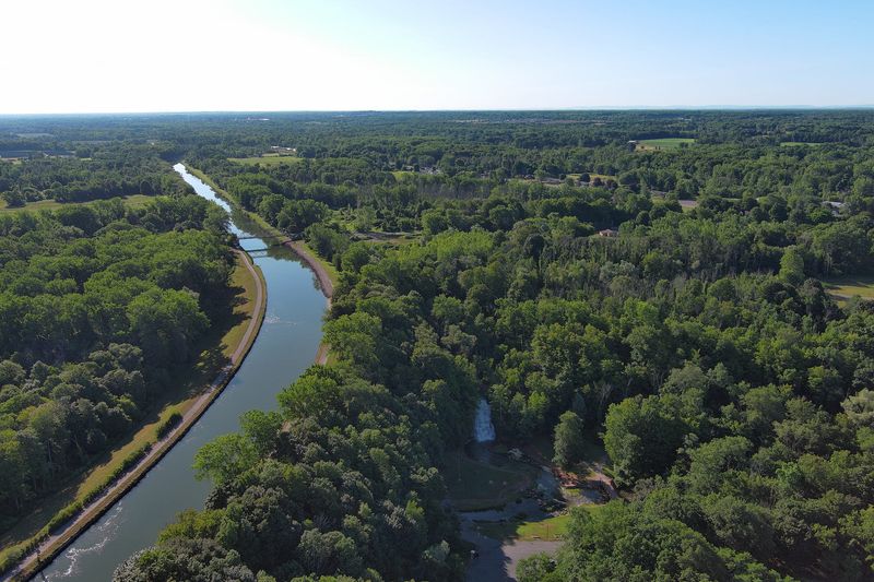 The Erie Canal goes by the village of Holley on July 22, 2025. The Holley Falls, below right, is man-made taking some of its water from the overflow of the Erie Canal.