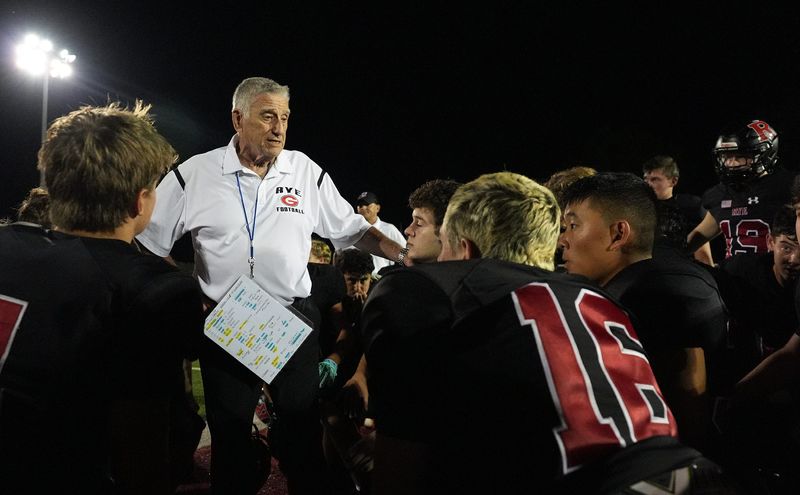Rye head coach Dino Garr talks with his players after their 42-28 win over Clarkstown North at Rye High School on Friday, September 26, 2025. With this win, Rye head coach Dino Garr notches his 365th win in his 50 years of coaching.
