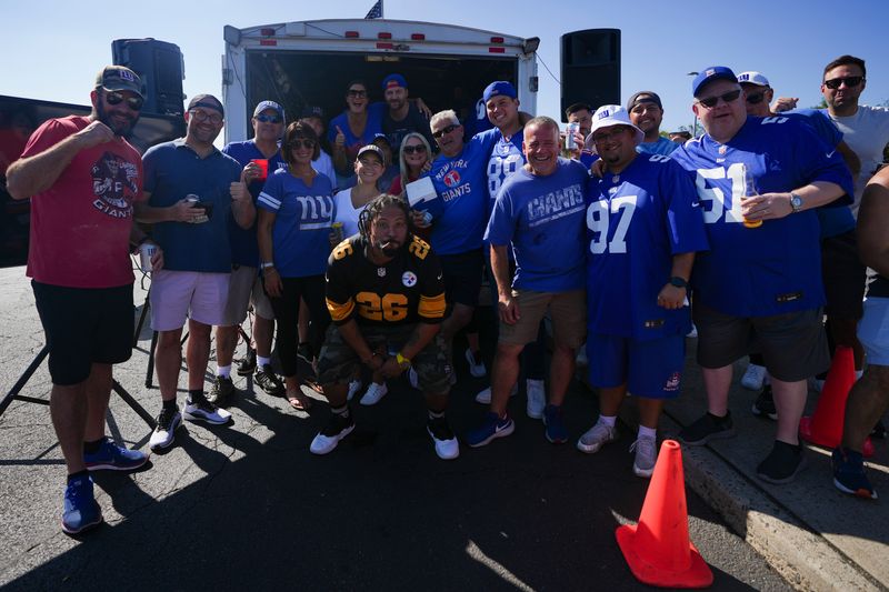 New York Giants fans pose for a photo while tailgating outside MetLife Stadium, Sep 28, 2025, East Rutherford, NJ, USA.