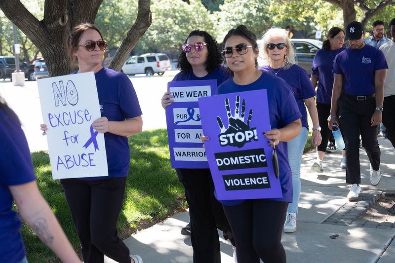 Participants carry signs reading “No excuse for abuse” and “Stop domestic violence” during the Domestic Violence Awareness Walk on Oct. 1, 2025, in downtown Amarillo.
