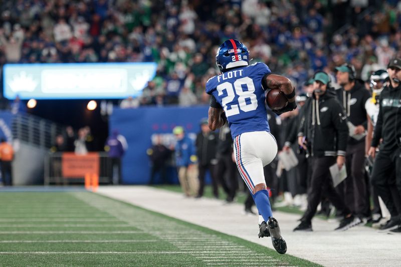 Oct 9, 2025; East Rutherford, New Jersey, USA; New York Giants cornerback Cor'Dale Flott (28) carries the ball after an interception against the Philadelphia Eagles during the fourth quarter of the game at MetLife Stadium. Mandatory Credit: Vincent Carchietta-Imagn Images