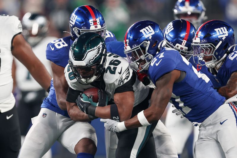 Oct 9, 2025; East Rutherford, New Jersey, USA; Philadelphia Eagles running back Saquon Barkley (26) carries the ball defended by New York Giants linebacker Bobby Okereke (58) and safety Tyler Nubin (27) during the first quarter of the game at MetLife Stadium. Mandatory Credit: Vincent Carchietta-Imagn Images