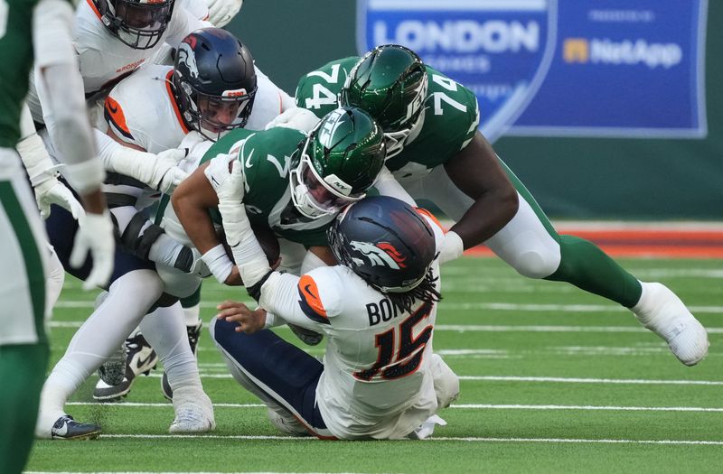 Oct 12, 2025; Tottenham, United Kingdom; New York Jets quarterback Justin Fields (7) is tackled by Denver Broncos linebacker Nik Bonitto (15) during an NFL International Series game at Tottenham Hotspur Stadium. Mandatory Credit: Kirby Lee-Imagn Images
