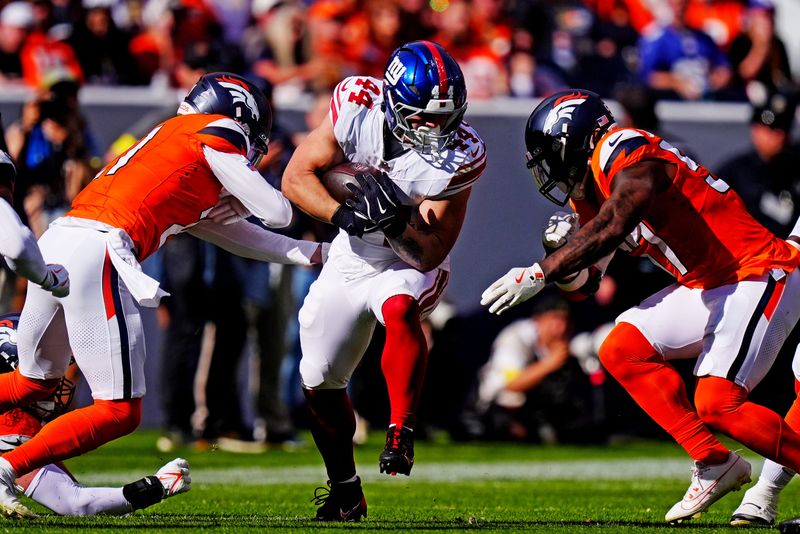 Oct 19, 2025; Denver, Colorado, USA; New York Giants running back Cam Skattebo (44) runs the ball against pressure from the Denver Broncos during the second half at Empower Field at Mile High. Mandatory Credit: Ron Chenoy-Imagn Images