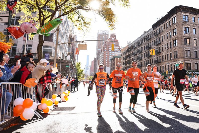 Crowd at left cheers as Liz Healy (second from left) and her teammates reach the 17-mile mark of the 2023 New York City Marathon.