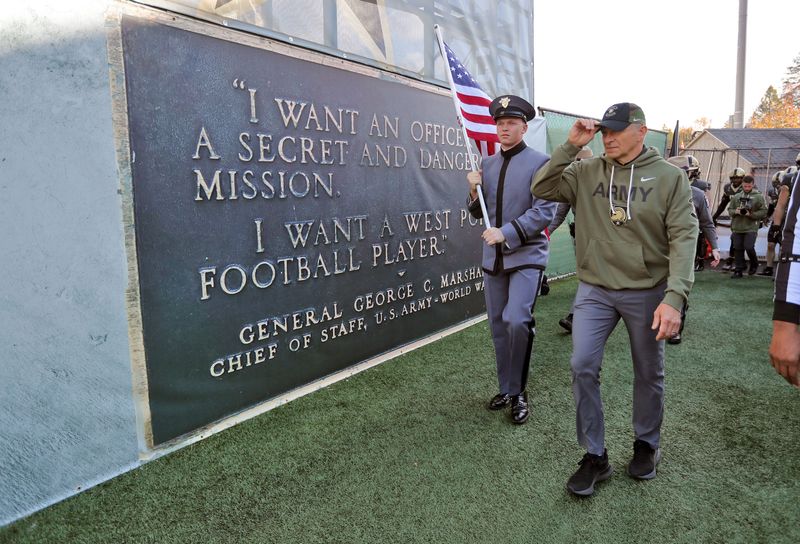 Nov 8, 2025; West Point, New York, USA; Army Black Knights head coach Jeff Monken and a cadet holding an American flag walk by the famed Marshall plaque at Michie Stadium before a game against the Temple Owls. Mandatory Credit: Danny Wild-Imagn Images