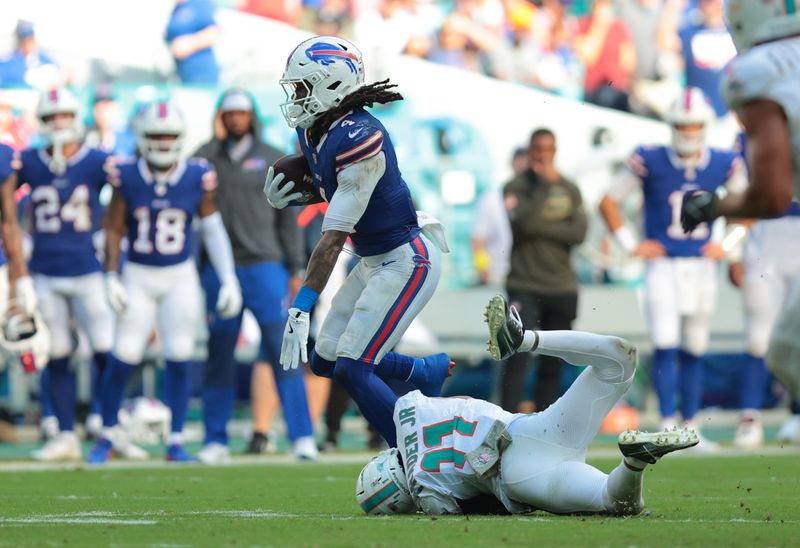 Nov 9, 2025; Miami Gardens, Florida, USA; Buffalo Bills running back James Cook III (4) runs against Miami Dolphins safety Dante Trader Jr. (11) during the second half at Hard Rock Stadium. Mandatory Credit: Sam Navarro-Imagn Images