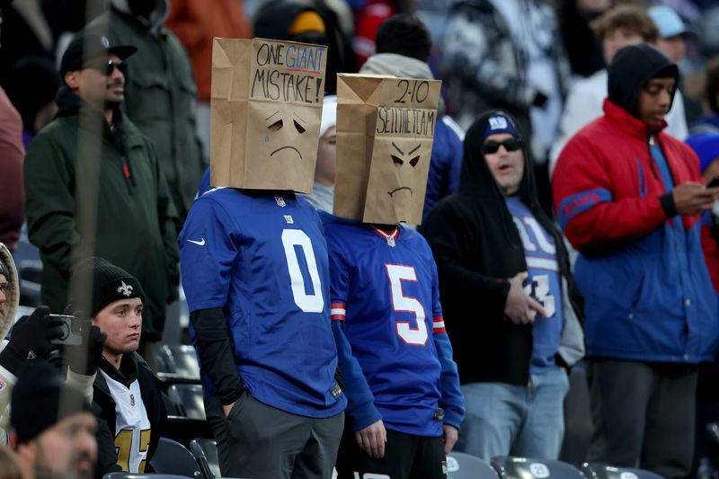 Dec 8, 2024; East Rutherford, New Jersey, USA; New York Giants fans wear paper bags on their heads during the fourth quarter against the New Orleans Saints at MetLife Stadium. Mandatory Credit: Brad Penner-Imagn Images