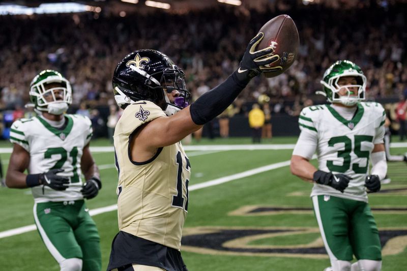 Dec 21, 2025; New Orleans, Louisiana, USA; New Orleans Saints wide receiver Chris Olave (12) crosses the goal line for a touchdown against New York Jets cornerback Brandon Stephens (21) and safety Dean Clark (35) during the third quarter at Caesars Superdome. Mandatory Credit: Matthew Hinton-Imagn Images