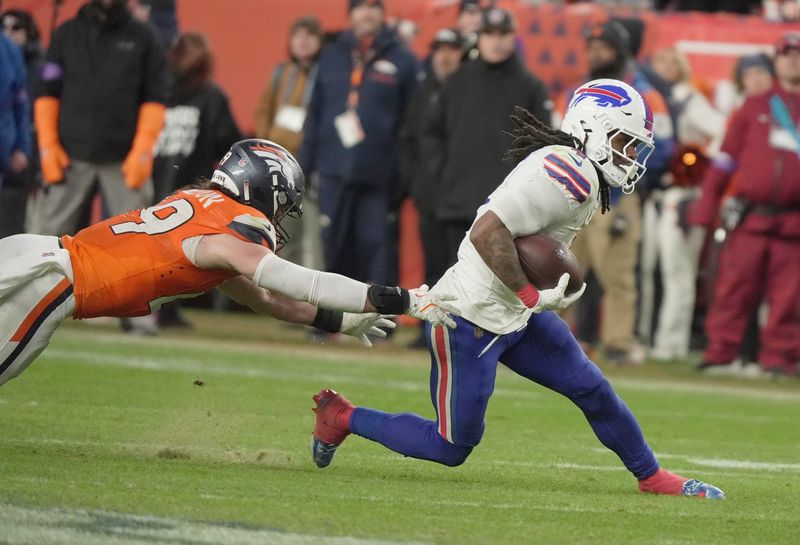 Buffalo Bills running back James Cook III avoids the reaching Broncos player during second half action at Empower FIeld at Mile High in Denver, Colorado on Jan. 17, 2026.