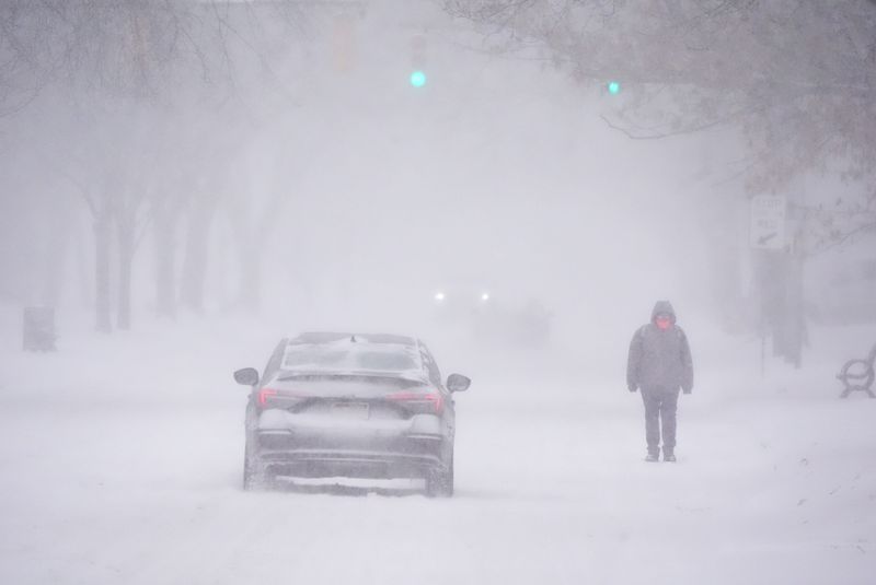Streets and sidewalks were snow covered causing cars to find a path and pedestrians to walk on the street on Jan. 25, 2026. A pedestrian makes their way west on East Avenue in Rochester.