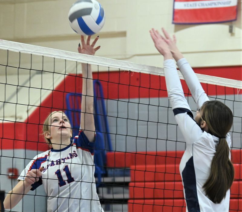 Avery Evans (left) plays the ball over the net for the New Hartford Spartans during the third game of Saturday's Section III quarterfinal sweep of the Central Valey Academy Thunder.