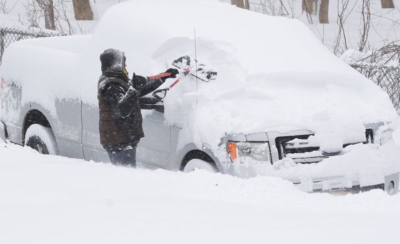 A man cleans the heavy snow off his car on Progress Street in Brewster, New York Feb. 23, 2026.