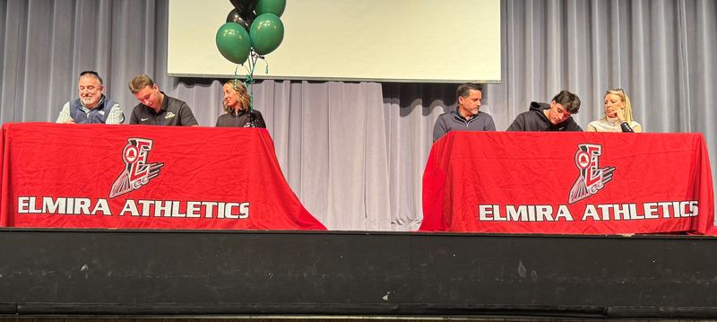 Aedan Palmer, left, and his cousin, Logan Palmer, join their families on the stage during Elmira High School's college signing ceremony Feb. 24, 2026 at the school's theater.