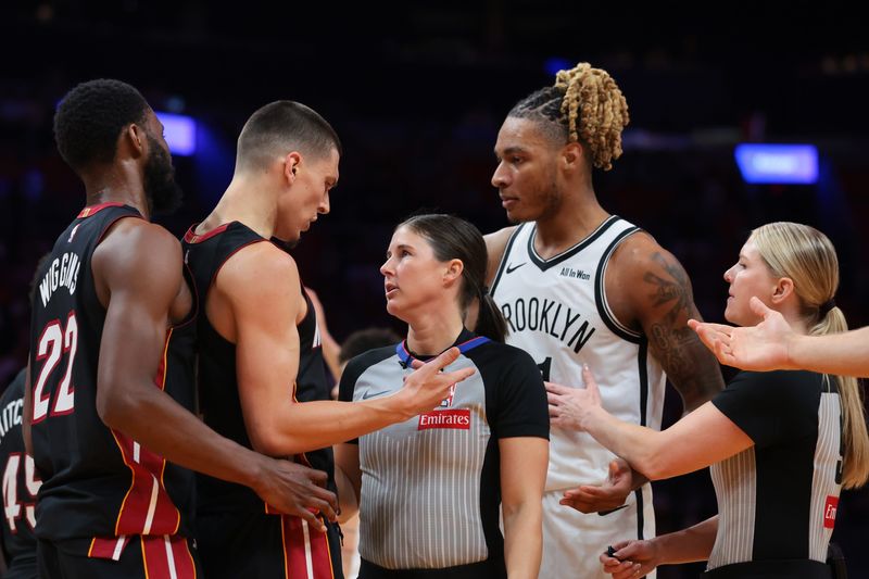 Mar 3, 2026; Miami, Florida, USA; referee Natalie Sago (9) stands in between Miami Heat guard Tyler Herro (14) and Brooklyn Nets forward Noah Clowney (21) as they argue during the second quarter at Kaseya Center. Mandatory Credit: Sam Navarro-Imagn Images