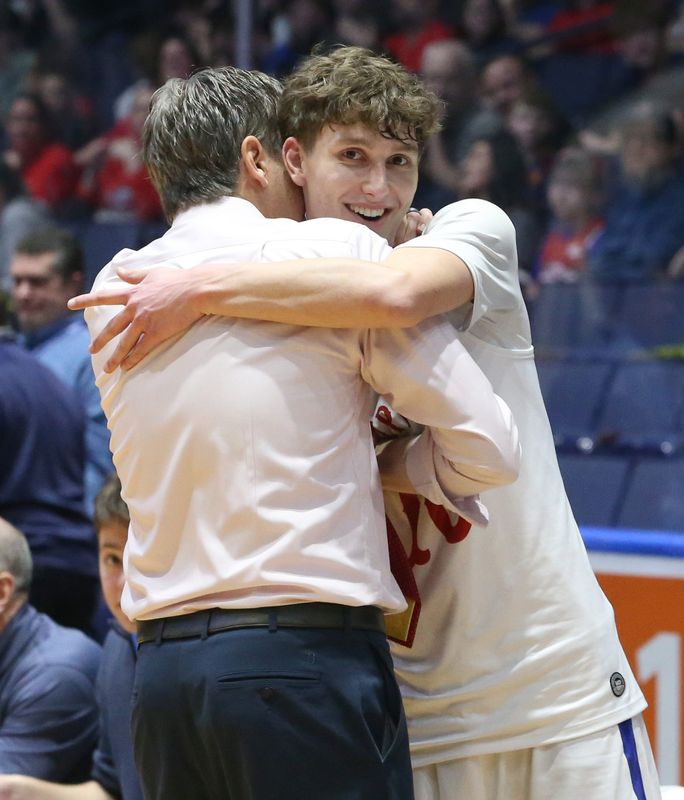 Fairport head coach Scott Fitch hugs senior Alex Grejda in the closing minute of the game during their Section V Class AAA boys basketball sectional finals Saturday, March 7, 2026 at Blue Cross Arena in Rochester.