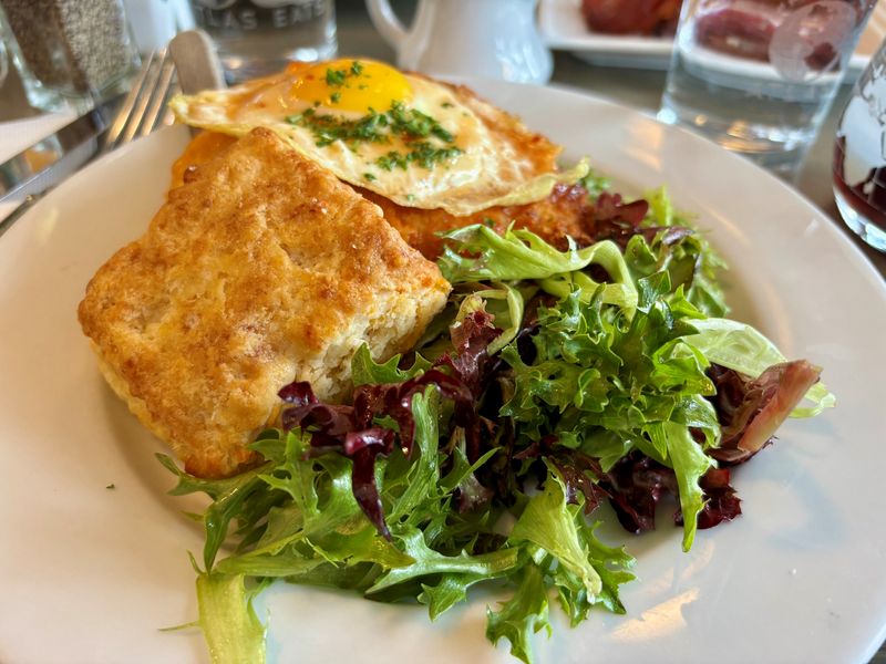 A chicken cutlet and sunny-side-up egg is served with cheddar biscuits and a salad at Atlas Eats in Irondequoit, New York.