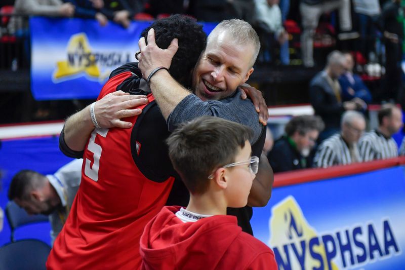 Penfield head coach Jason Ellis, right, hugs Aaron Hardaway after their win in a NYSPHSAA Class AA Boys Basketball Championship semifinal Friday, March 20, 2026 in Binghamton, N.Y. Penfield advanced to the Class AA final with a 69-66 overtime win against Seton Catholic (IV).