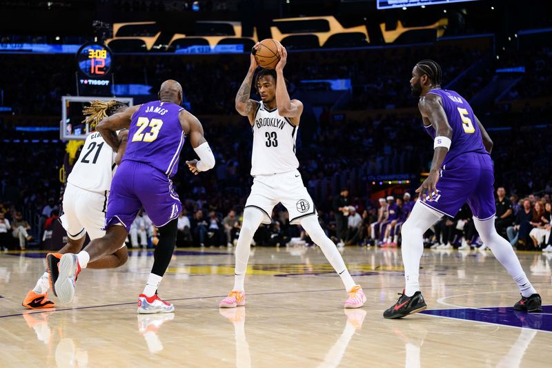 Mar 27, 2026; Los Angeles, California, USA; Brooklyn Nets center Nic Claxton (33) controls the ball against Los Angeles Lakers center Deandre Ayton (5) during the first half at Crypto.com Arena. Mandatory Credit: William Liang-Imagn Images