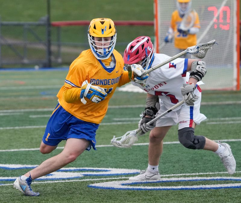 Irondequoit’s Dylan Carey weaves the ball over the middle past Fairport’s Marco Provenzano during their Section V boys lacrosse matchup Thursday, April 2, 2026 at Fairport High School.