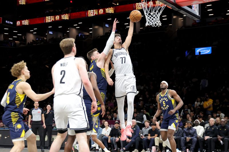 Feb 11, 2026; Brooklyn, New York, USA; Brooklyn Nets guard Ben Saraf (77) dunks against Indiana Pacers center Micah Potter (11) during the second quarter at Barclays Center. Mandatory Credit: Brad Penner-Imagn Images