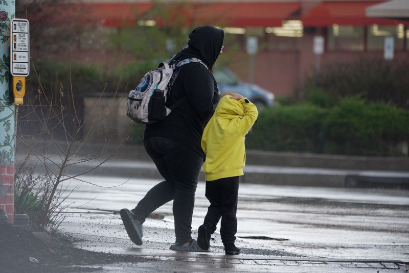 A thunderstorm rolled through Rochester on April 14, 2026. A mother and child cross Winton Road at Blossom Road in Rochester.