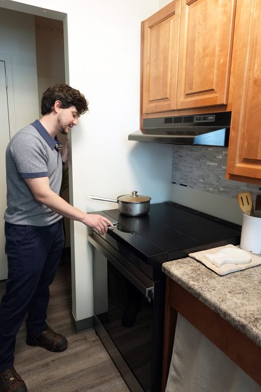 Construction manager Juan Barragan, a consultant for the Mulford Corp., demonstrates how to use the new induction stove in an apartment at the Palisade Towers housing complex which is undergoing a $35-million project to convert the complex from gas to electric service April 14, 2026 in Yonkers.