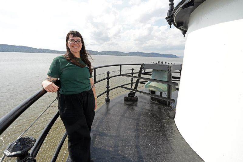 Curator Julia Snook stands near the original fog bell on the balcony of the Tarrytown Lighthouse in Sleepy Hollow, April 15, 2026. The lighthouse, managed by Westchester County Parks, reopened for tours with a fresh look after an arson and vandalism spree in 2025.